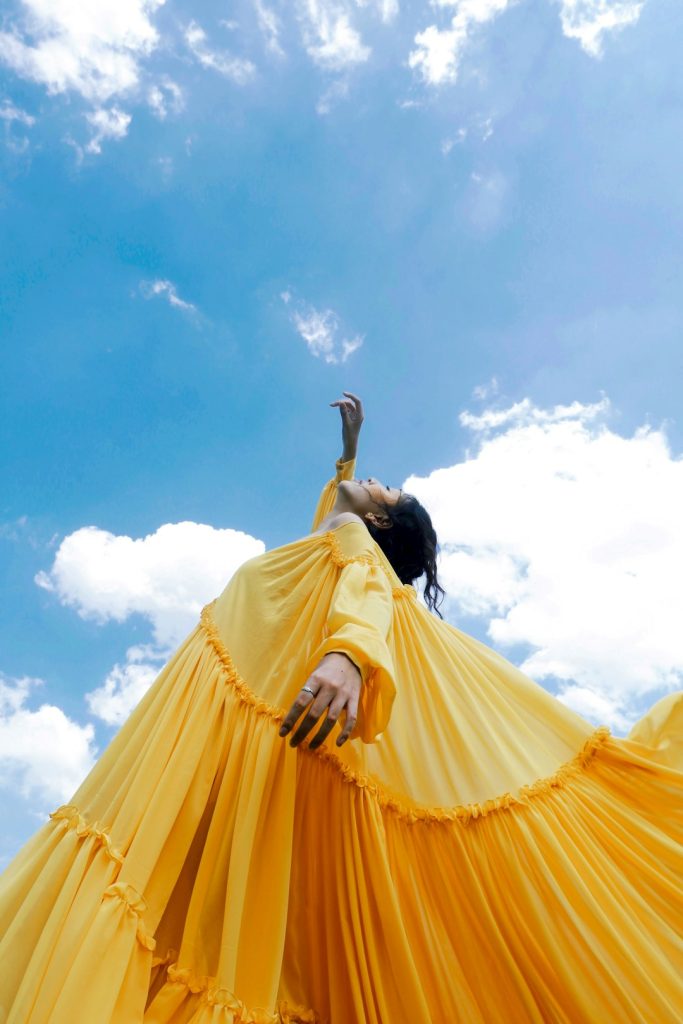 woman-wearing-yellow-long-sleeved-dress-under-white-clouds-and-blue-sky-during-daytime-fo-zqd7wqio